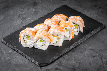 appetizing sushi roll philadelphia with avocado cheese cucumber and shrimp on a black stone plate