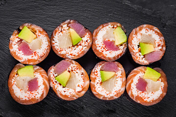 appetizing sushi roll with tuna salmon escolar crab and avocado on a black stone plate