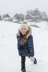 Fototapeta na wymiar Ein Mädchen spielt im Schnee, Schneeballschlacht. Schneefall im Winter. 