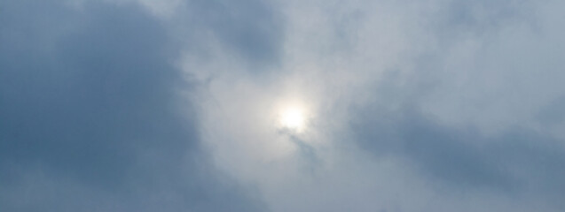 The sky is covered with dense gray clouds, through which the sun can barely see