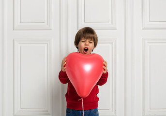 surprised boy holding red balloon heart on white background