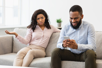 Angry Black Woman Looking At Boyfriend, Man Using Phone