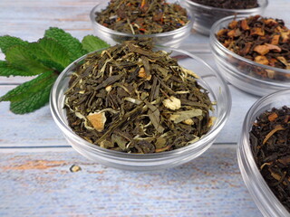 Bowl filled with various types of tea on a vintage wooden background 
