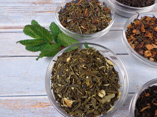 Bowl filled with various types of tea on a vintage wooden background 