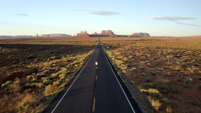 Drone footage of man running in Monument Valley, along empty forest Gump highway in Utah