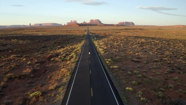 Drone footage of man walking in monument valley, along empty forest Gump highway in Utah