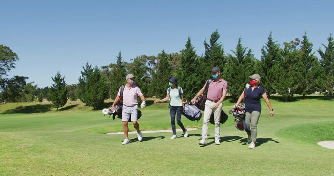 Senior people wearing face masks walking with their golf bags at golf course