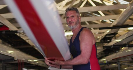 Senior caucasian man carrying a rowing boat - Powered by Adobe