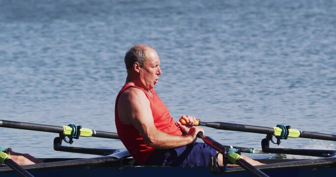 Two senior caucasian men rowing boat on a river