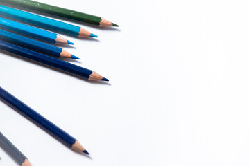 Some different colored wooden pencil crayons placed in a row in front of a white isolated background