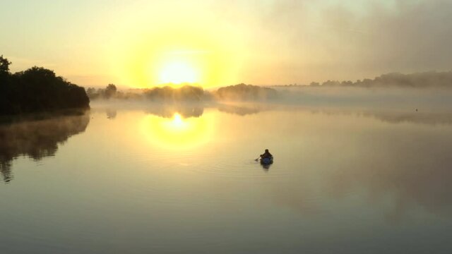 Drone footage of misty sunrise morning of people kayaking on a lake in the English countryside
