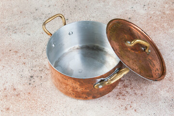 Old copper casserole on a concrete background.