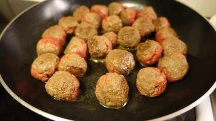 Homemade meatballs are slowly cooking in the pan