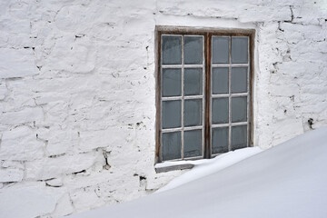 old window in the old wall of an old barn in winter with snow