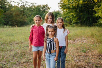 Fototapeta premium A group of cheerful girls are smiling and playing in the Park during sunset. Children's summer camp