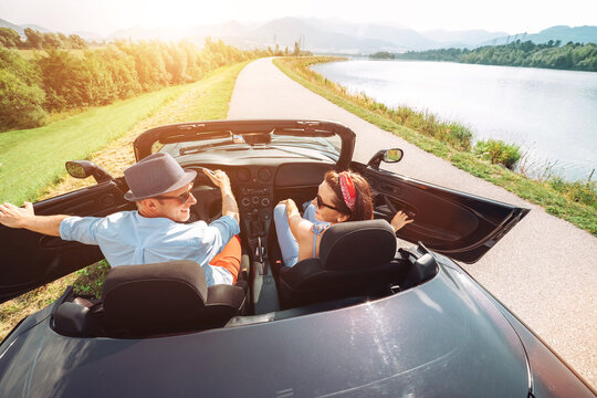 Couple in love getting into the convertible auto cabriolet and starting a trip. Couple honeymoon, traveling or vacation concept image.