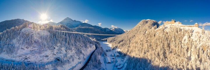 pedestrian suspension bridge over hermitage and ruin ehrenberg in reutte in the snow-covered winter with sunbeams