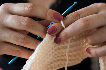 The woman knits woolen clothes. Knitting needles.