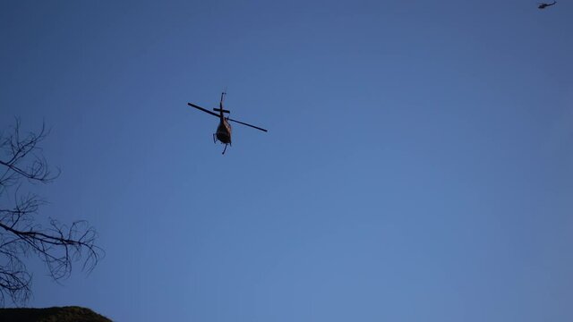 firefighting helicopter dropping water on a large wildfire