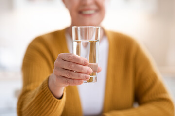 Closeup of glass with spring water in old woman hand
