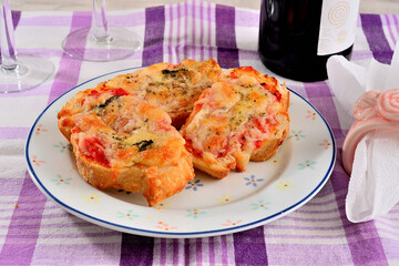 Brusquetas de pão italiano com queijo parmesão e tomate servidas num prato e vinho