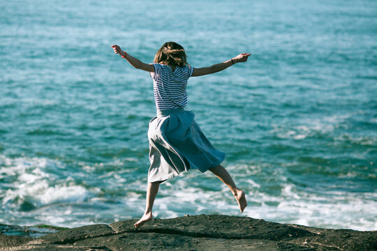 Young dance woman is engaged in choreography on the ocean coast.