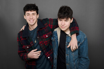 two guys hugging like friends watching on camera on a grey background