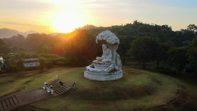 4k Concrete Naga Buddha statue in the morning. Pan around a Seven-headed king cobra sheltering the Buddha while meditating, Mucilanda. Khao Yai National Park in Thailand. Sunrise glares