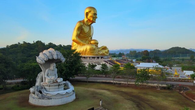 4k Naga Buddha statue. Pan around Golden statue of Luang Phor Thuat and a Seven-headed king cobra sheltering the Buddha while meditating, Mucilanda. Khao Yai National Park in Thailand. Sunrise glares