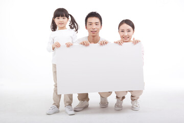 Portrait of a family of three holding whiteboard