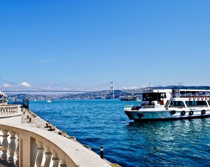 ISTANBUL, TURKEY: Ciragan Palace was once the palace of Ottoman sultans and is now a luxury hotel. A view of the Bosphorus or Bosporus Strait and bridge from Europe to Asia with ferry boat. 