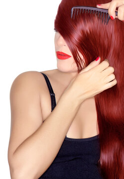 Hair coloring and hair care concept with a young redhead woman combing her long, shiny, healthy hair