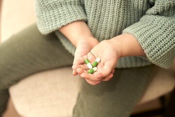  Children's hand with the medication in the capsules is white and green. Selective focus. Copy space.