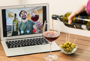 Young woman clinking with wine on video call party online with her boyfriend during coronavirus outbreak - Focus on laptop