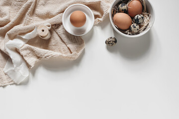 Easter decorative frame, banner. Spring still life with natural quail and hen eggs, ceramic bowls and linen napkins isolated on white table background. Neutral feminine styled stock photo, top view.