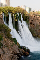 Obraz premium A waterfall erupts into the sea from a great height on a sunny day near the city