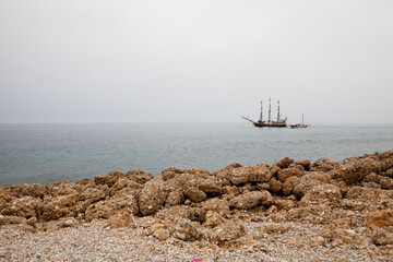 Fototapeta na wymiar Sailboat in the sea near the rocky coast
