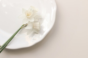 Obraz na płótnie Canvas Styled stock photo. Spring, Easter feminine desktop scene with white narcissus, daffodils flowers on porcelain plate. Beige table background. Floral composition, web banner. Flat lay, top view.
