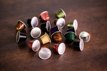 High angle photography of aluminum coffee capsules scattered around over wooden surface in front of white background. Aluminum is great ecological alternative for plastic coffee capsules.