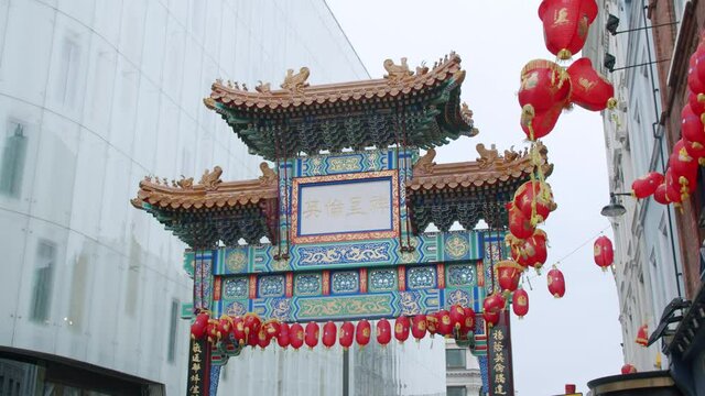 London's beautiful Chinatown entrance gate with Chinese lanterns swaying in the wind on an overcast day in slow motion.