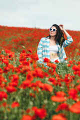 Obraz na płótnie Canvas young pretty woman in sunglasses at the field of poppy flowers