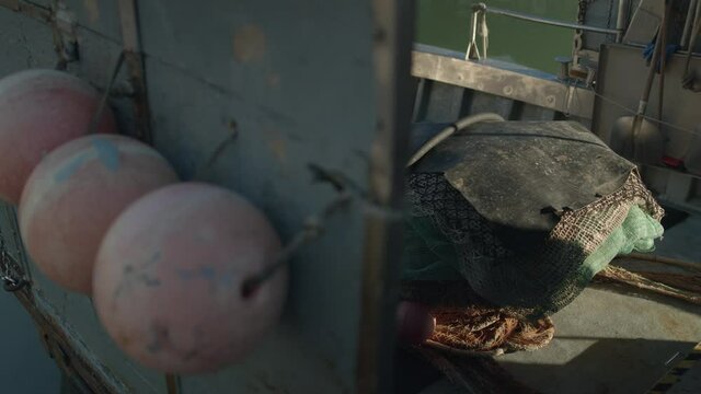 Slow-motion reveal shot of the deck of a fishing boat with bets, ropes and other tools.