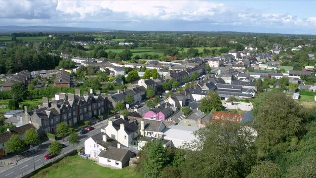 Flying over cute Irish village with cosy street and beautiful houses. Aerial.