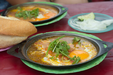 Vietnamese street food breakfast: fried eggs dish with a fresh French baguette. Hoi An, Vietnam