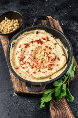 Hummus paste with chickpea and parsley in a bowl. Black background. Top view