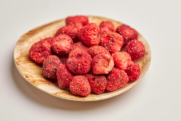 Close-up of dehydrated strawberries in wooden bowl isolated on white background.