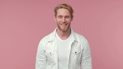 Smiling cheerful bearded young man 20s years old in white casual clothes isolated on pastel pink color wall background studio. People lifestyle concept. Looking camera showing ok okay gesture blinking