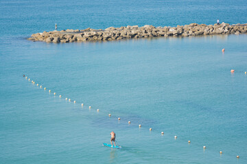 Man surfing on a SUP (Standup paddleboarding) in the water of the Mediterranean Sea, Tel Aviv,...