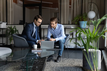 Colleagues using laptop, discussing strategy, sharing ideas, working on project in modern office...