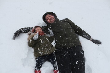 parent and child playing with snow.